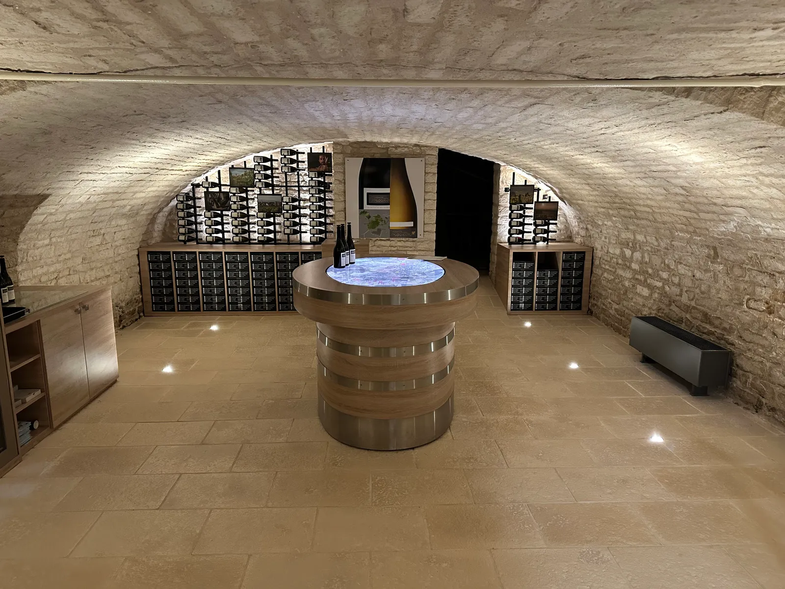 A vaulted stone tasting cellar with bottles and a round table in the Côte Chalonnaise