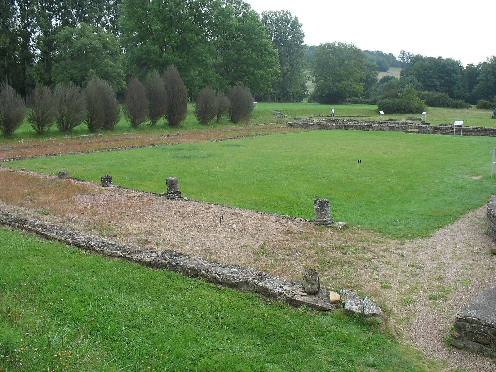 Low walls of the Gallo-Roman baths and exercise court at the Fontaines Salées, among lawns and trees