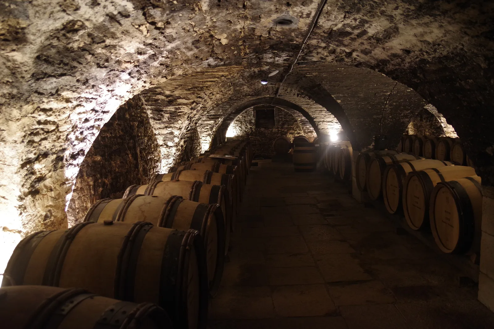 An arched passage between rows of barrels in a cellar of the Hospices de Beaune