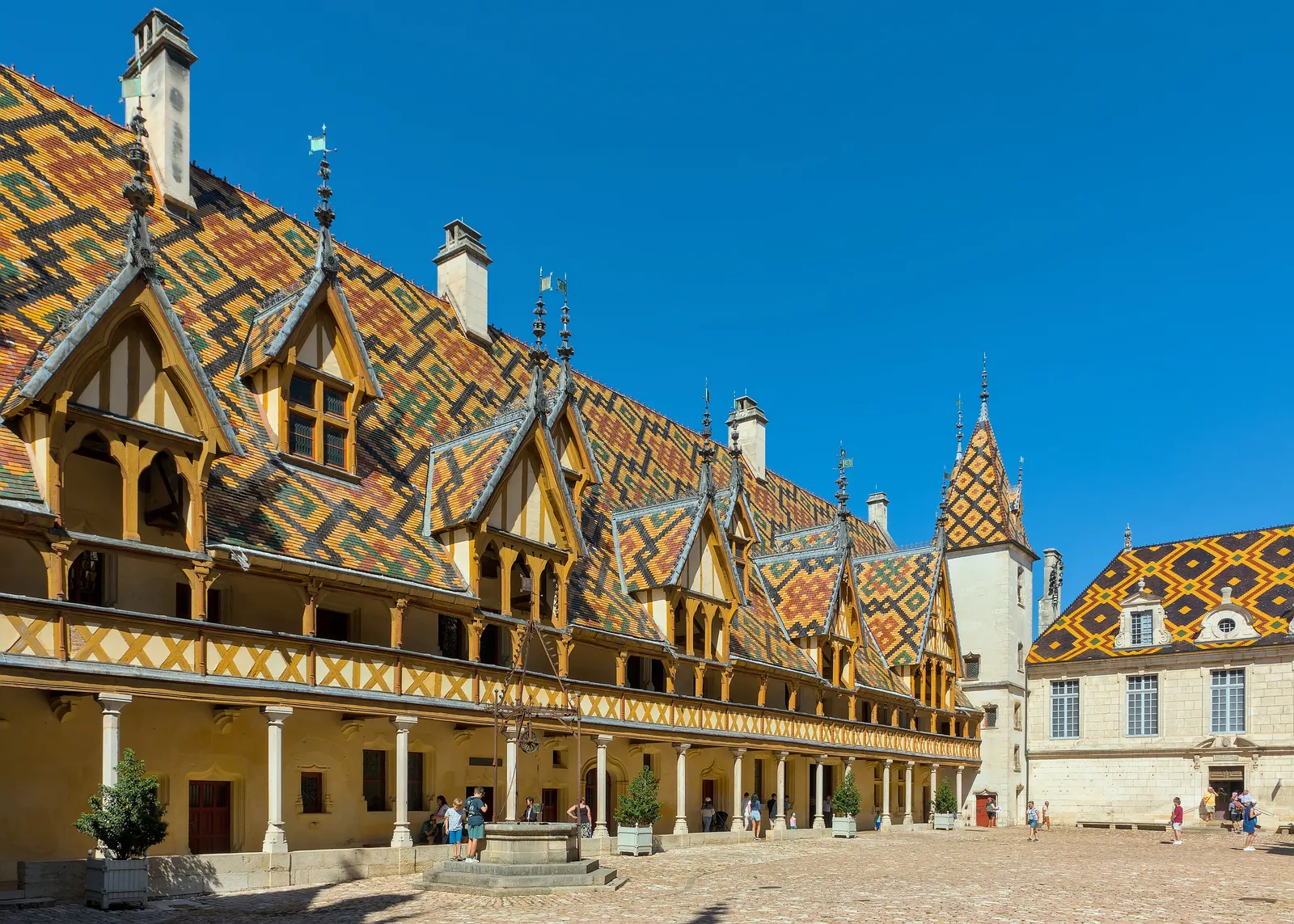 The courtyard of the Hôtel-Dieu in Beaune: its long glazed tile roof, timber gallery and corner tower