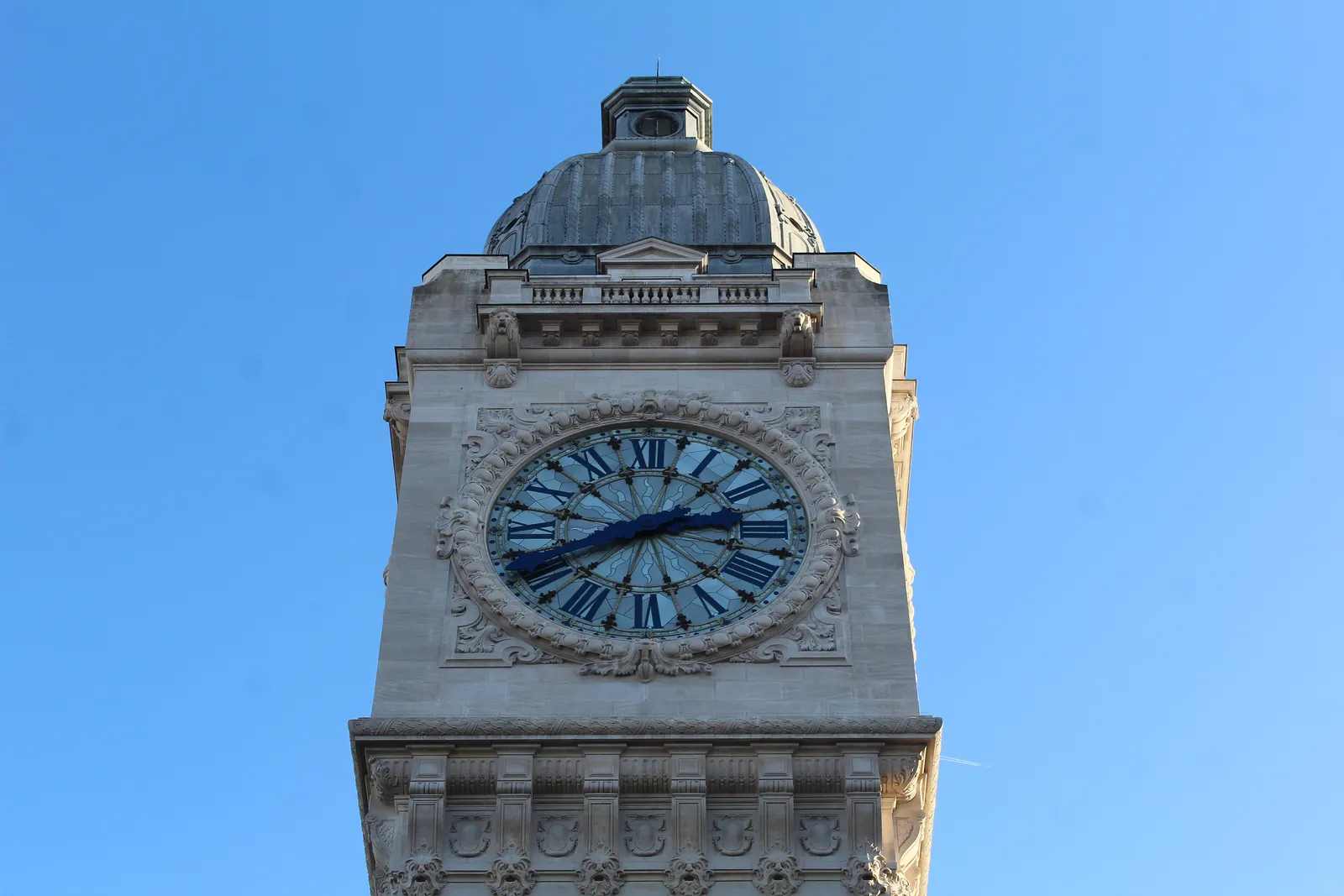 The clock tower of the Gare de Lyon in Paris against a clear blue sky